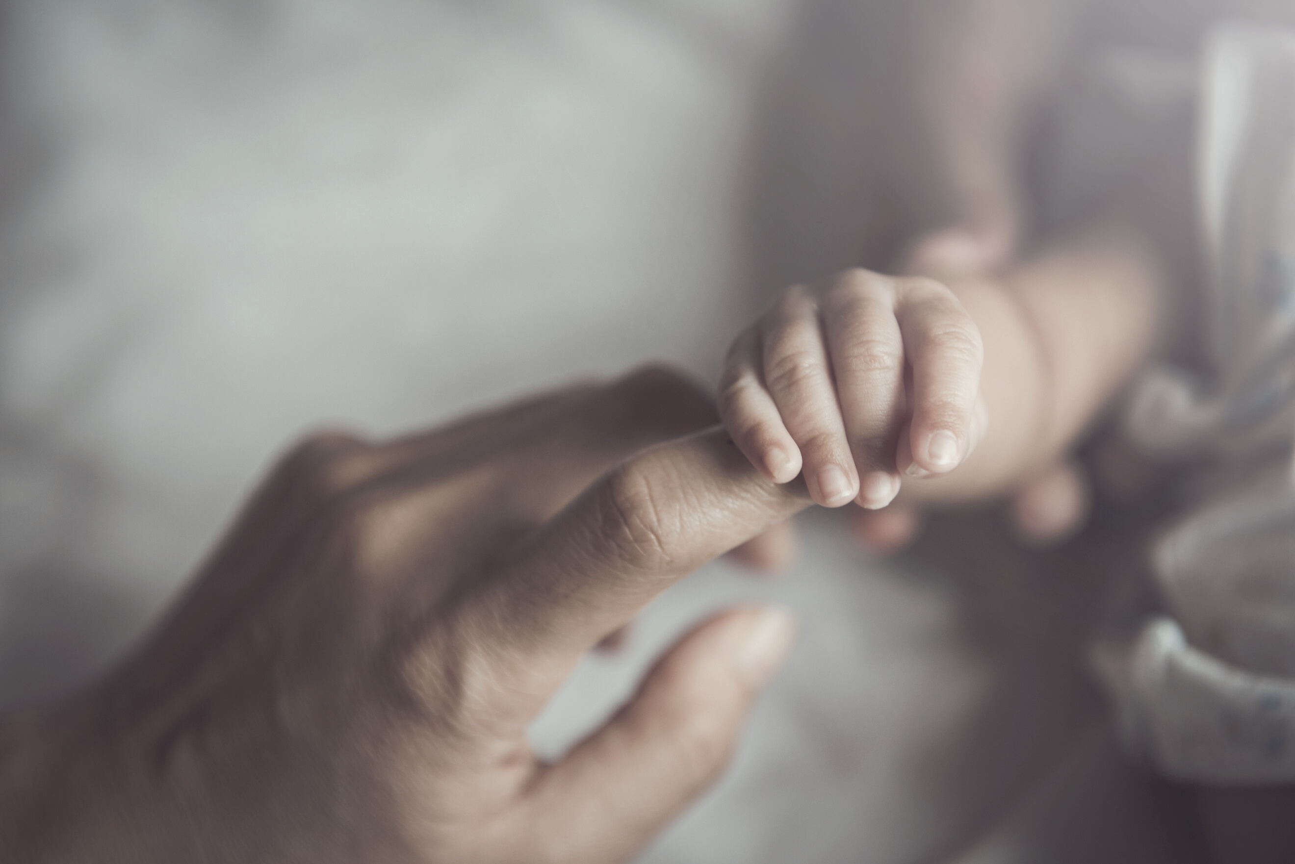 Newborn baby holding mother's hand.