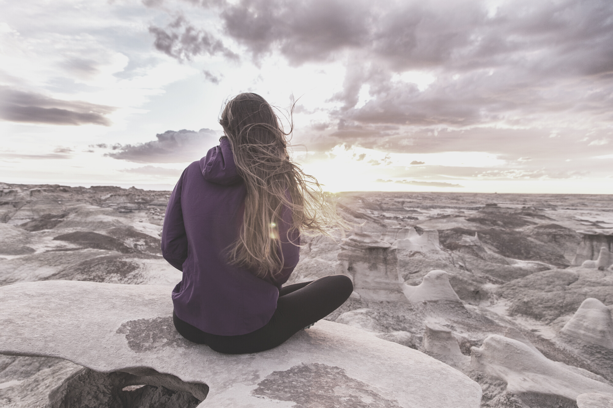 Woman Wearing Purple Hooded Jacket Sitting on Rock